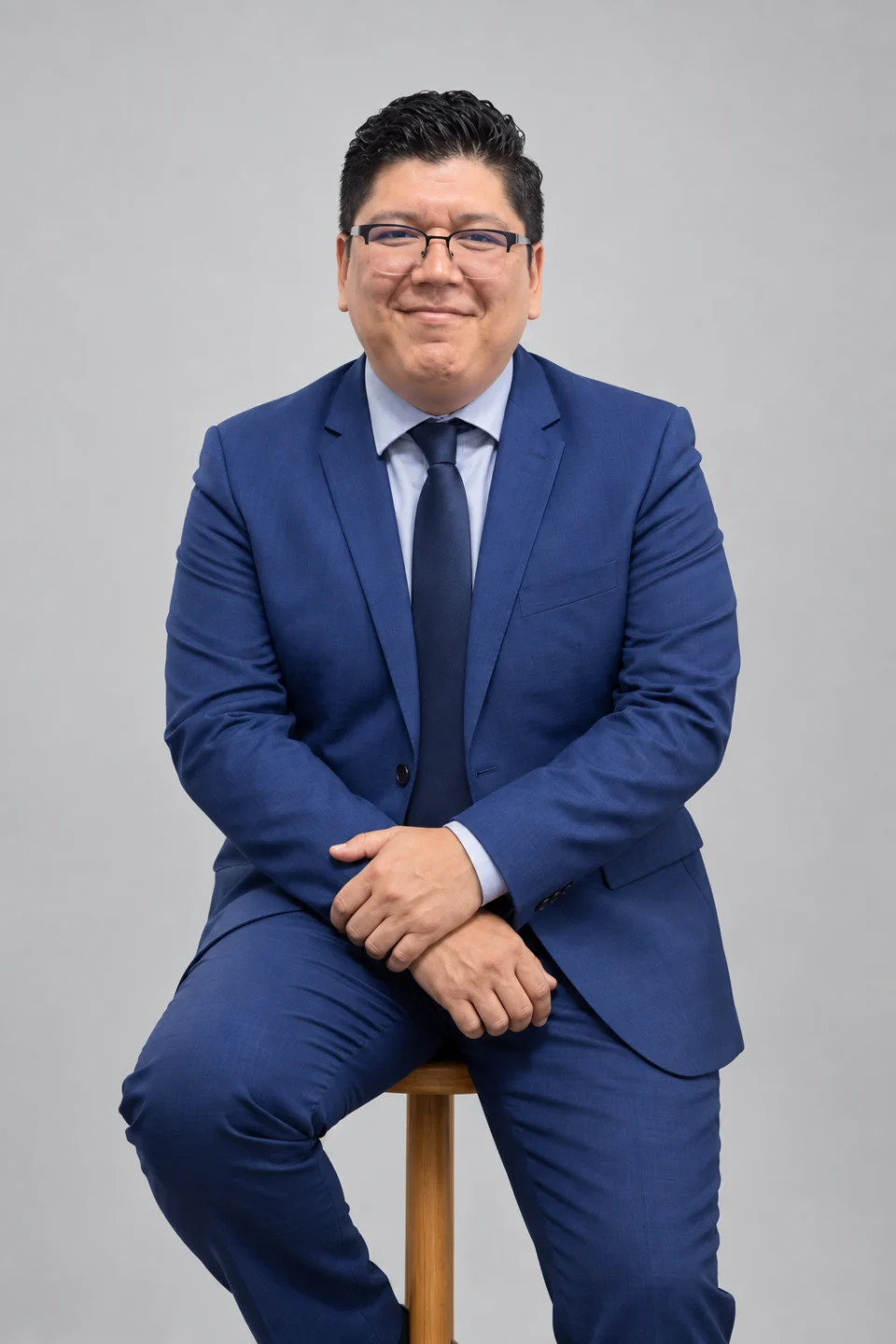 Dr. Luis Ramírez Corona con traje azul, sentado en un banco de madera
